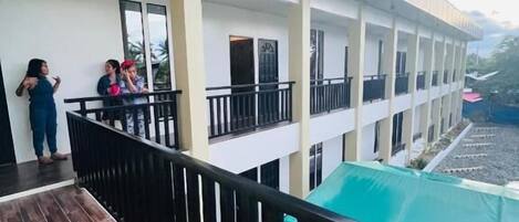 A multi-story building with balconies, a covered outdoor area, and a swimming pool.