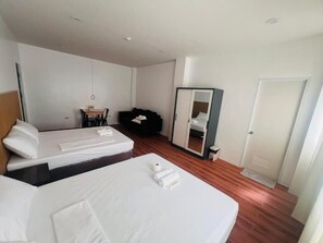 A hotel room with two beds, a small table, a mirror, and a wardrobe. - Hearthstone Suite & Cafe (Laguindingan)