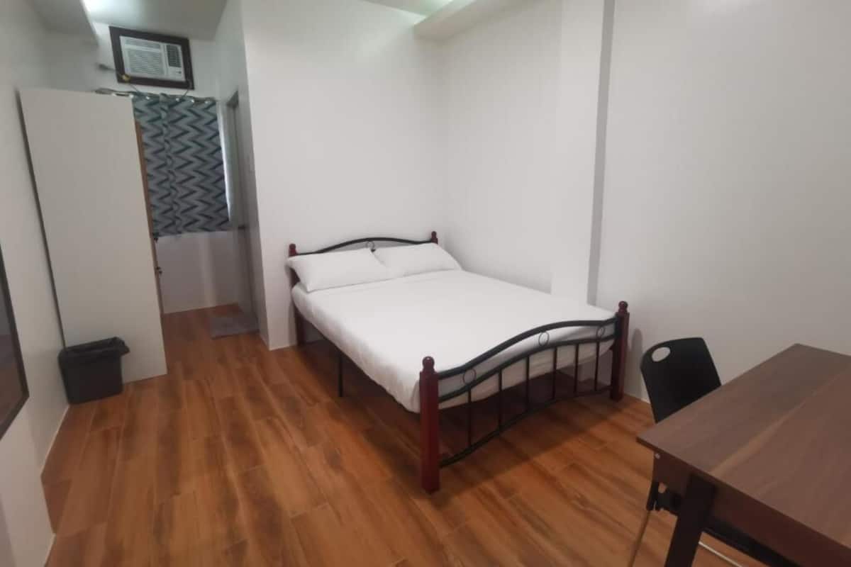 Une chambre avec un lit simple, un plancher en bois, un bureau et une chaise.
