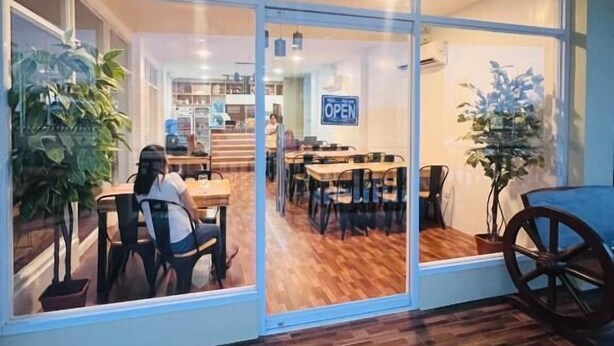 Un restaurante con un tabique de vidrio, suelo de madera y un cartel que indica que está abierto.