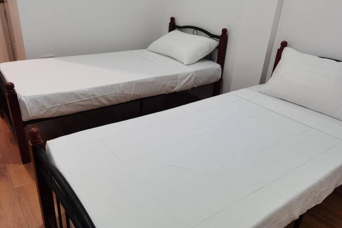 Une chambre avec deux lits simples, chacun doté d’un matelas blanc et d’un oreiller assorti.