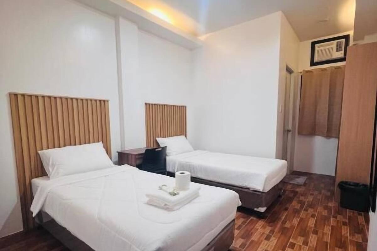 Une chambre d’hôtel avec deux lits, un plancher en bois et un luminaire au plafond.