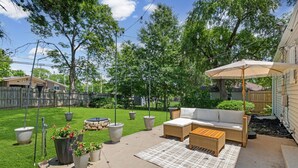 A backyard patio with outdoor furniture, a pergola with string lights, and a well-maintained lawn. - Walk to Martin City + Sleeps 6 + Yard + Fire Pit (Kansas City)