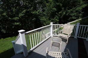 Eine Holzterrasse mit weißen Geländern und zwei Stühlen.