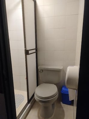 Un bany petit i funcional amb un vàter, un paperer blau i un dispensador de tovallons.