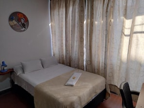 A hotel room with a bed, a desk with a lamp, and a chair. - Hotel Rico Campo (Armenia)