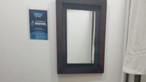 A bathroom with a sink, mirror, and a blue sign on the wall.