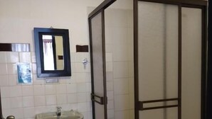 A bathroom with a shower enclosure, a sink, and a toilet.
