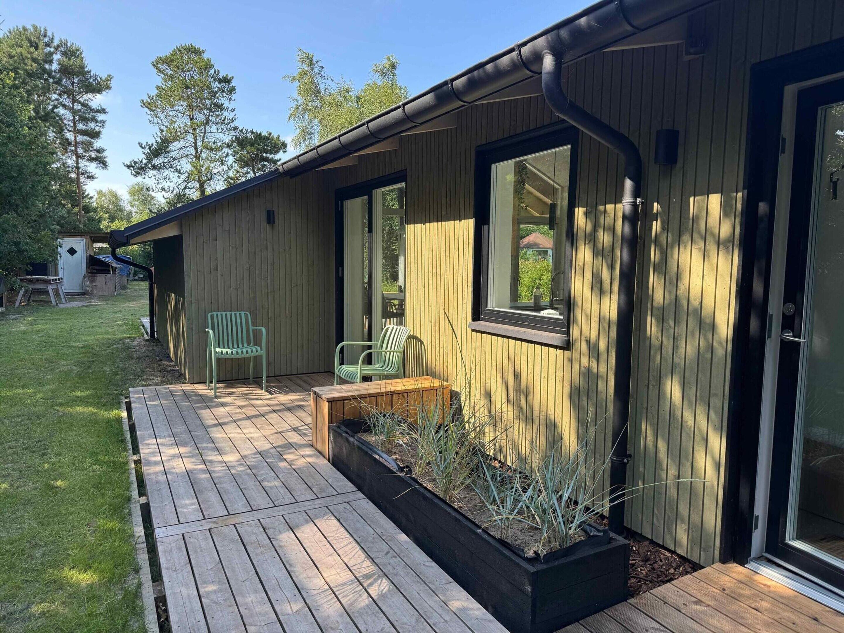 A wooden building with a deck, two chairs, and a window.