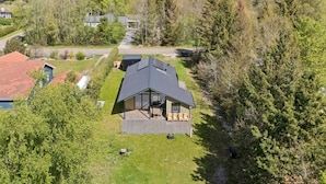 A lakeside cabin with a deck, surrounded by trees and a view of the lake. - 4 Star Holiday Home in Storvorde (Storvorde)