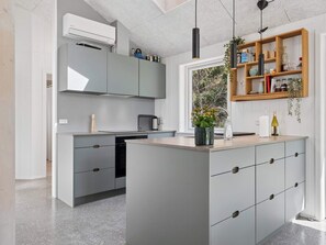 Una cucina moderna con mobili grigi, un'isola centrale, un forno integrato e una finestra vista verde.