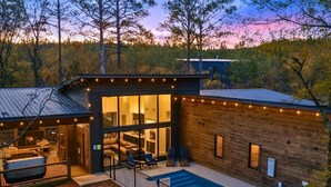 A modern house with a swimming pool, outdoor seating, and string lights. - NEW! Heated Pool, Hot Tub, Outdoor Lounge, Games (Broken Bow)