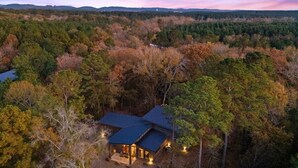 A house surrounded by forest with a view of distant hills. - NEW! Heated Pool, Hot Tub, Outdoor Lounge, Games (Broken Bow)