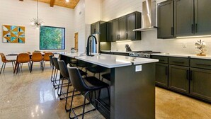 A modern kitchen with a central island, dark cabinets, and a wooden ceiling. - NEW! Heated Pool, Hot Tub, Outdoor Lounge, Games (Broken Bow)