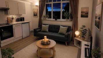 A modern kitchen with a dining area, a sofa, and a coffee table with candles.