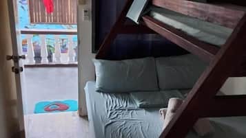 Ein Zimmer mit einem Etagenbett, einer Holztür und Blick auf einen Balkon mit Geländer.
