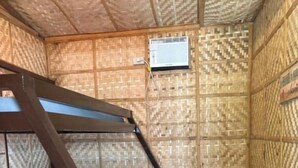 Une chambre avec un lit superposé, une petite poubelle et un climatiseur fixé au mur.