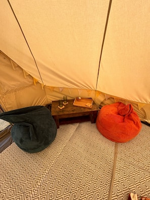 A tent interior with a patterned floor, a small table with a tray, and two bean bags.