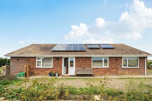 A residential building with a brick facade, a tiled roof, and solar panels installed on the roof. - Sea Palling 2 bed /2 bath beach apartment Sleeps 4 (Norwich)