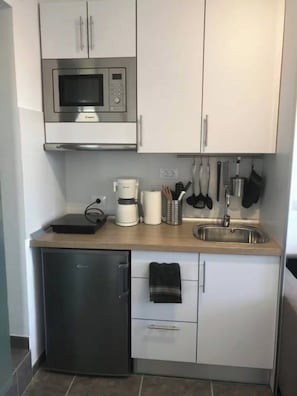 Eine kleine Küche mit Mikrowelle, Kaffeemaschine und kleinem Kühlschrank.