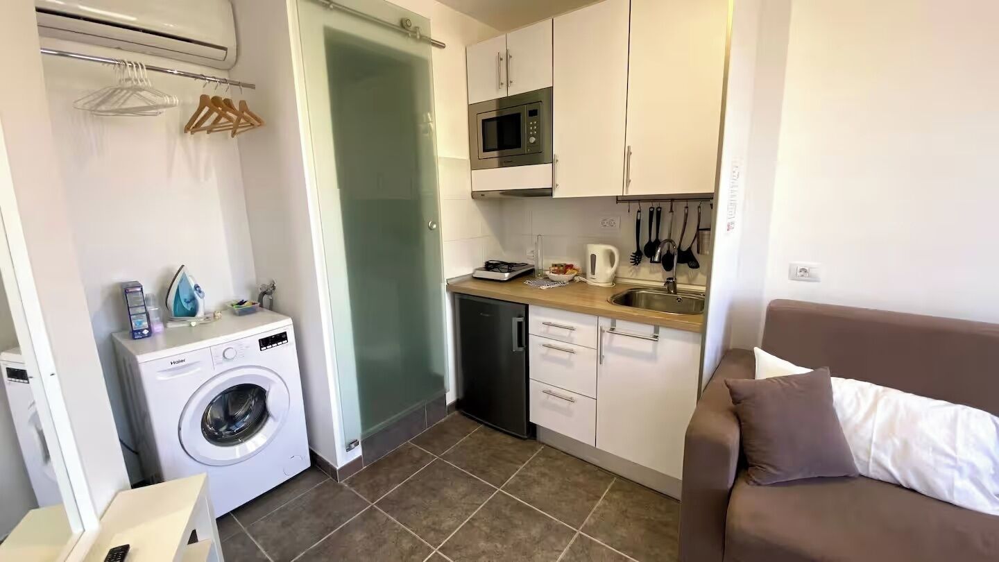 A compact kitchen with a washing machine, a microwave, and a sink.