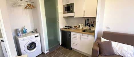 A compact kitchen with a washing machine, a microwave, and a sink.