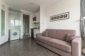 Ein modernes Wohnzimmer mit Sofa, Essbereich und einer Küche inklusive Mikrowelle.