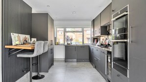 Une cuisine moderne avec des meubles de couleur grise, un plan de travail en bois et un tabouret de bar.