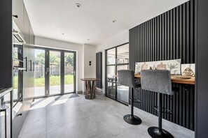 A modern kitchen with a dining area, large windows, and a view of the outdoors. - Aylesbury - Sleeps 6 - Parking - Central Location (Aylesbury)