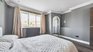 Une chambre avec un grand lit, une fenêtre avec des rideaux, un radiateur et un miroir.