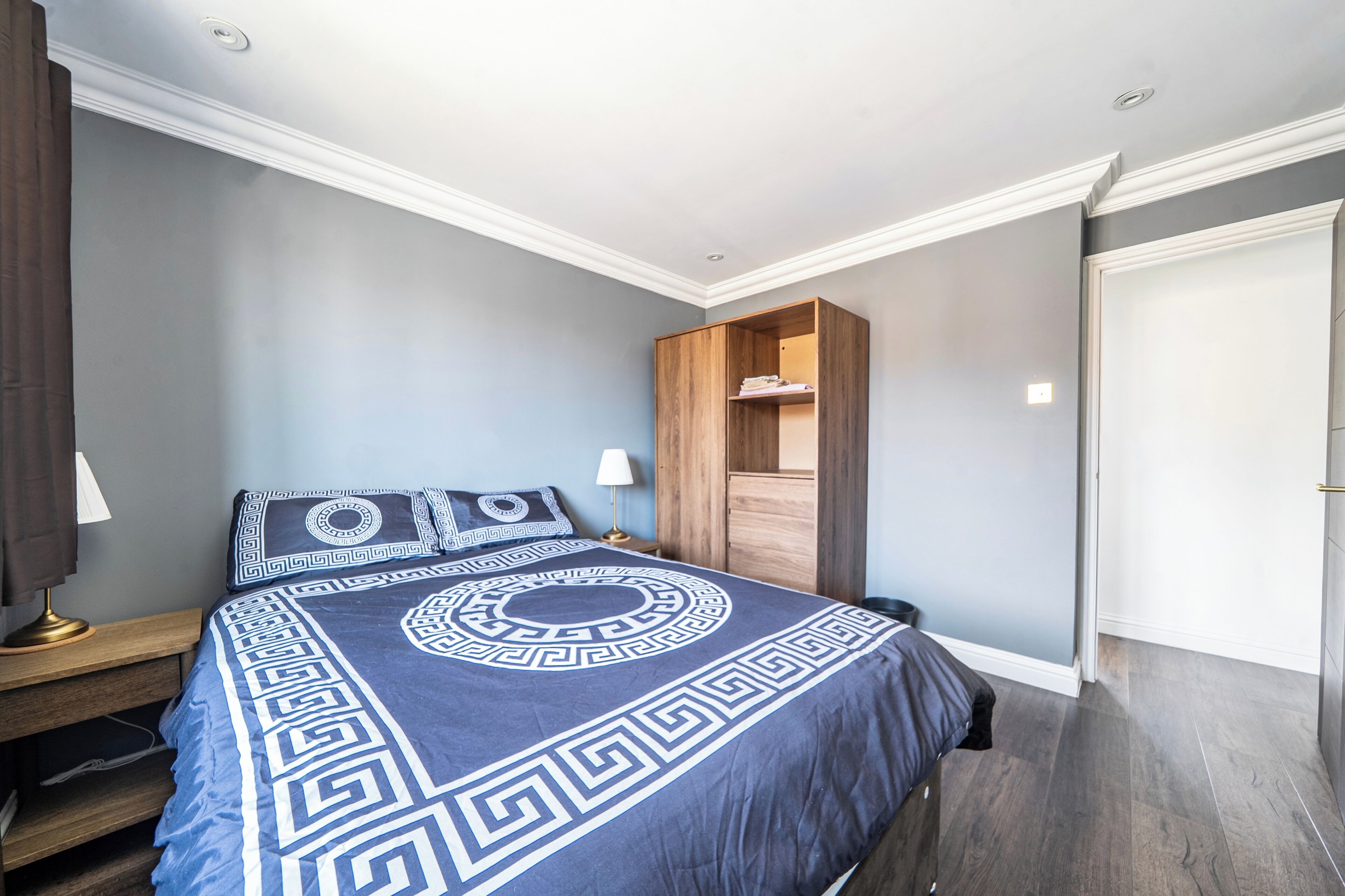 Een slaapkamer met een bed, nachtkastjes, een kledingkast en een deur.