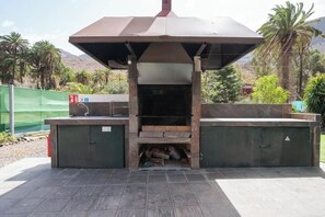 Ein Grillbereich im Freien mit Schornstein, zwei Schränken und Fliesenboden.