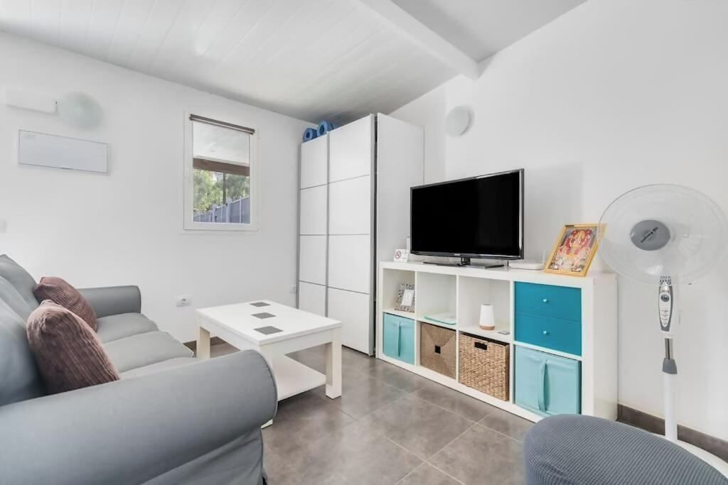 A modern living room with a sofa, a TV, a small table, and a cabinet with storage.