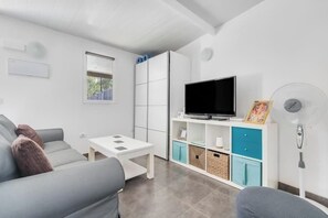A modern living room with a sofa, a TV, a small table, and a cabinet with storage. - Finca Apartament Near Maspalomas (San Bartolomé de Tirajana)