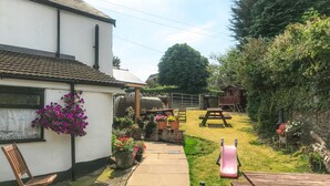 A garden with a patio, a wooden bench, a picnic table, and a play area. - Brewery Lodge Sleeps 4 (Lydney)
