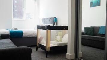 A modern bedroom with two beds, a window, a sofa, and a glass partition.