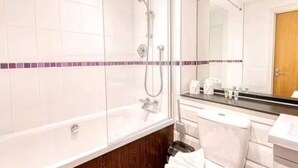 Un baño con ducha envuelta en vidrio, lavamanos y espejo.