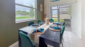 A dining area with a table set for six, large windows, and a view of the outdoors. - Designer Home with Community Pool Near Apollo Beach (Ruskin)