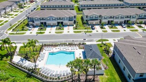 A residential area with multiple two-story houses, a swimming pool, and a well-maintained lawn. - Designer Home with Community Pool Near Apollo Beach (Ruskin)