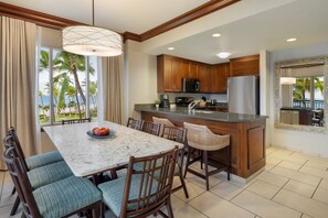 A modern kitchen with wooden cabinets, a stainless steel refrigerator, and a marble island. - Marriott's Maui Ocean Club Walk to Beach & Whalers Village (Lahaina)