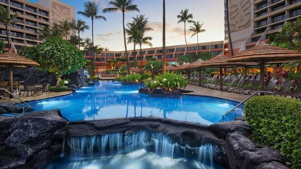 A hotel pool with a waterfall feature, surrounded by palm trees and lounge chairs. - Marriott's Maui Ocean Club Walk to Beach & Whalers Village (Lahaina)
