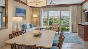 A dining area with a table, chairs, and a bowl of fruit. There is a sofa and a television in the room. - Marriott's Maui Ocean Club Walk to Beach & Whalers Village (Lahaina)