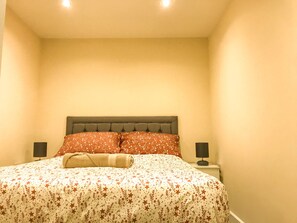 A bedroom with a bed, two bedside tables, and a headboard. - Apartment Sleeps 4 with Parking (Lydney)
