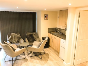 A compact living space with a dining area, a kitchenette, and a door leading to another room. - Apartment Sleeps 4 with Parking (Lydney)