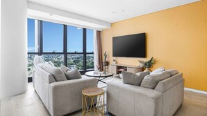 Un salon moderne avec deux canapés, une table basse ronde et un téléviseur à écran plat fixé au mur.