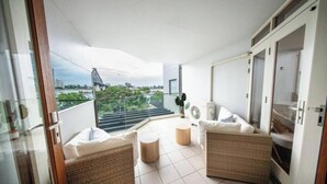 Un balcon doté de meubles en osier, d’un ventilateur et offrant une vue sur le paysage urbain et sur des montagnes russes.