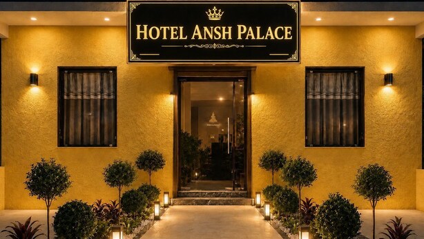 Ein Hotel Eingang mit einem Schild, das 'HOTEL ANSH PALACE' zeigt, einem mit Pflanzgefäßen gesäumten Weg und einer gut beleuchteten Fassade.