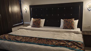 Ein Bett mit gemustertem Überwurf, einem dunklen Kopfteil und zwei dekorativen Wandleuchten.