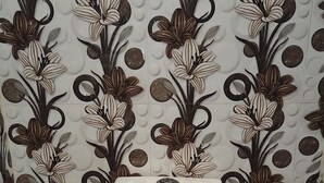Eine Toilette mit weißem Sitz und Deckel vor einer Wand mit einem floralen Fliesendesign.