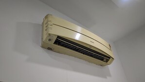 Eine Wand-Klimaanlage mit sichtbarem Markenname, Bedienfeld und Lüftungsschlitz.